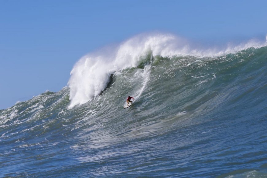 Surfista em ação nas ondas grandes da Praia do Cardoso durante o CBSurf Big Wave Mormaii, com o Farol de Santa Marta ao fundo