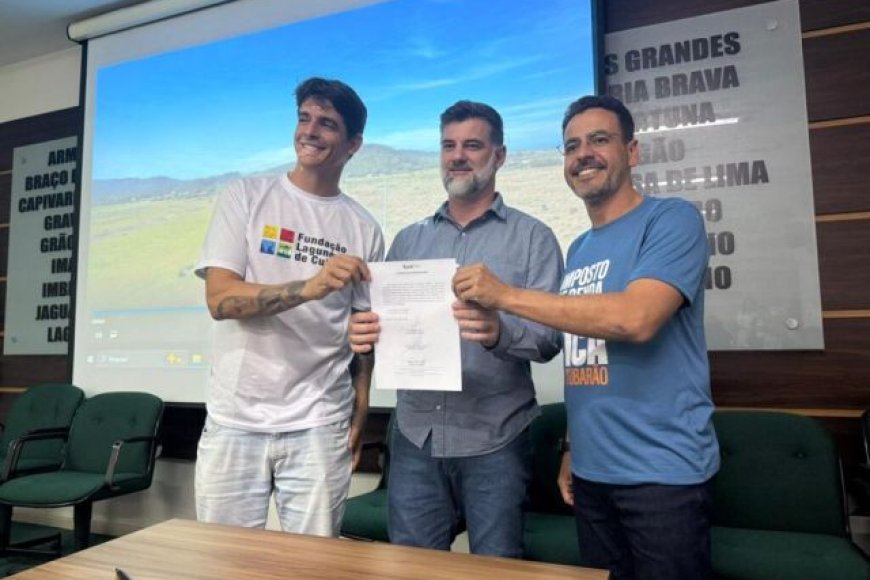 Trecho da Rodovia Aggeu Medeiros em construção, com pavimentação avançada e paisagem de transição entre Tubarão e Laguna ao fundo.