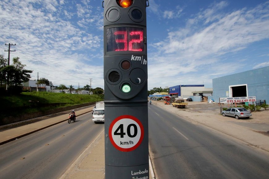 Ilustração de rodovia estadual com lombada eletrônica, veículos em movimento e símbolos de segurança viária em estilo geométrico.