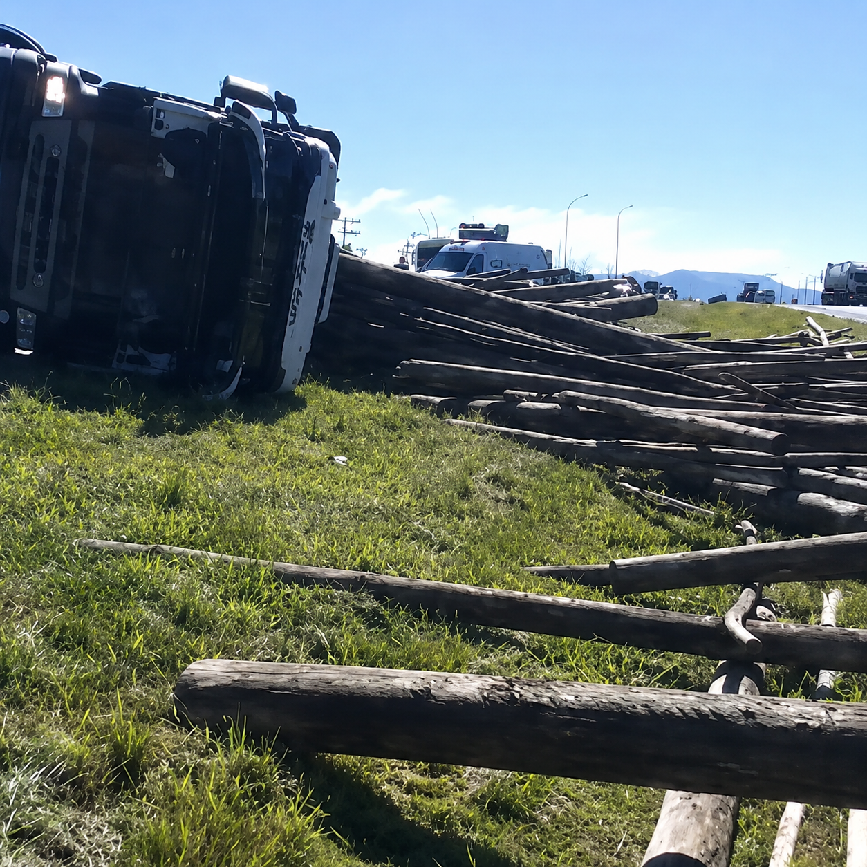 Caminhão tombado na BR-101 em Imbituba com carga de madeira espalhada pela pista; equipes de emergência e PRF atuam no local.