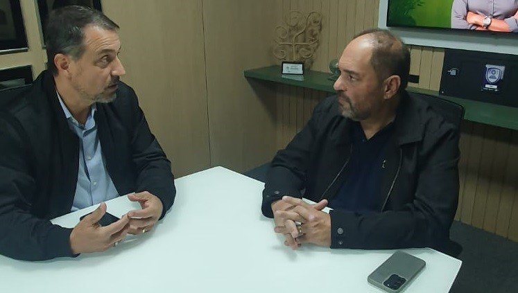 Silhueta de figura em pódio diante de lideranças empresariais, representando anúncio de pré-candidatura a deputado federal em ambiente corporativo.